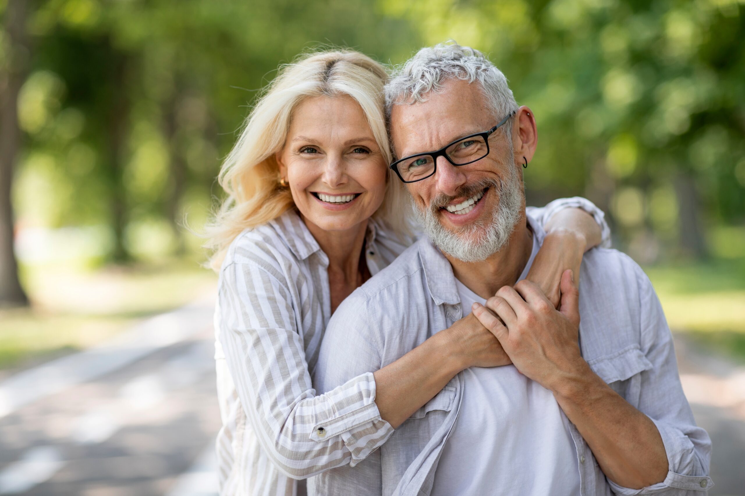 Portrait of cheerful older couple hugging and smiling at camera