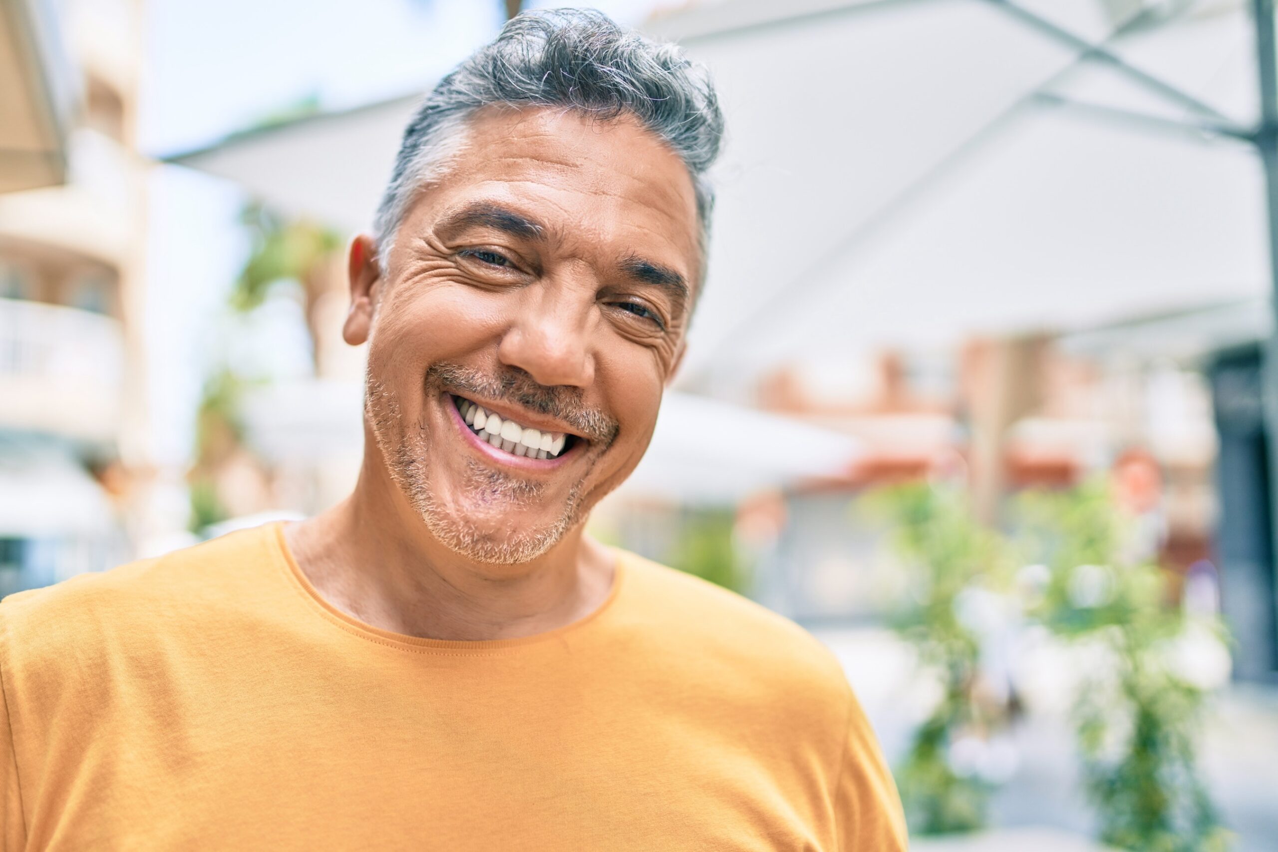 Middle age grey-haired man smiling happy walking at street of city.